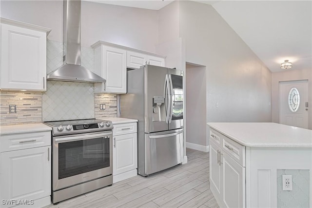 kitchen with tasteful backsplash, stainless steel appliances, wall chimney exhaust hood, light countertops, and vaulted ceiling