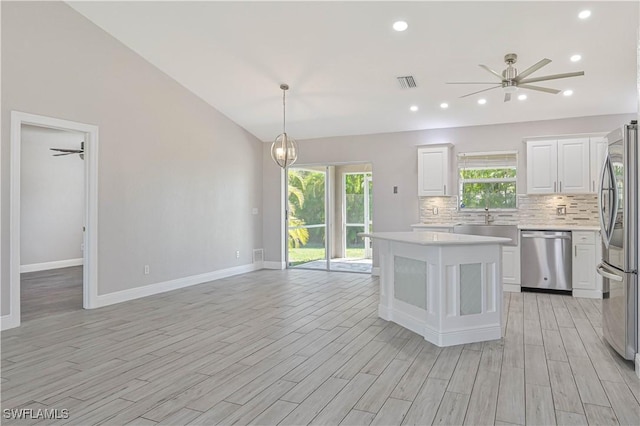 kitchen with visible vents, backsplash, light countertops, vaulted ceiling, and stainless steel appliances