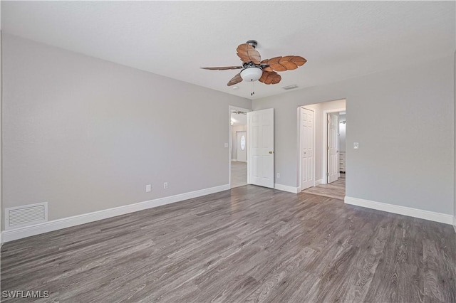 empty room featuring visible vents, baseboards, wood finished floors, and a ceiling fan