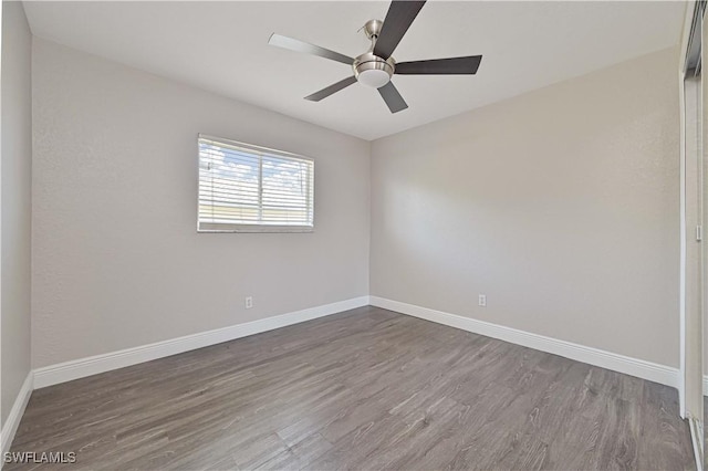 empty room featuring a ceiling fan, dark wood-type flooring, and baseboards