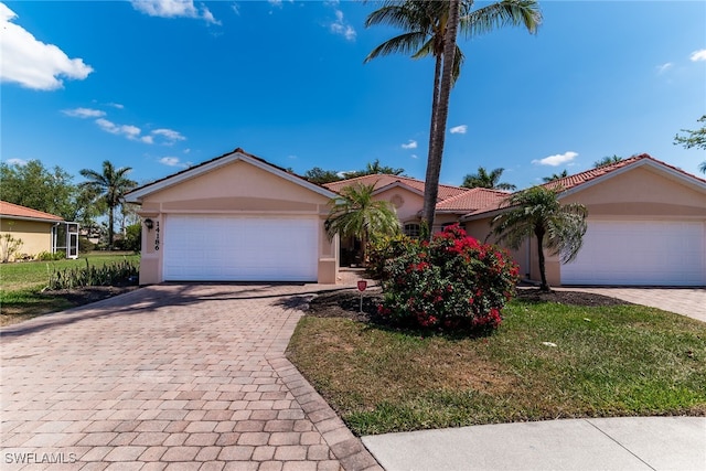 single story home with decorative driveway, a tiled roof, an attached garage, and stucco siding