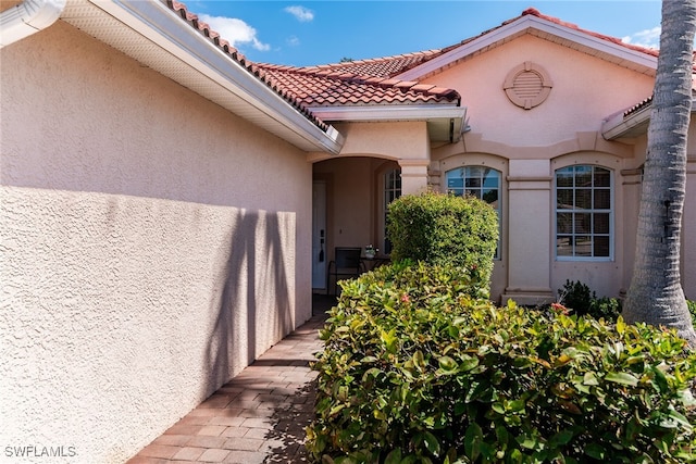 property entrance with a tile roof and stucco siding