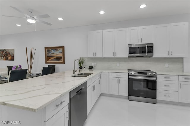 kitchen with backsplash, appliances with stainless steel finishes, a peninsula, and a sink