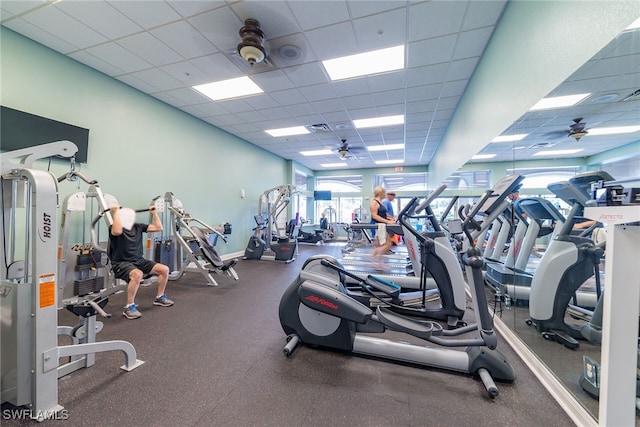 gym with visible vents, a paneled ceiling, and a ceiling fan