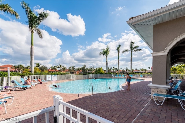 community pool with a patio and fence