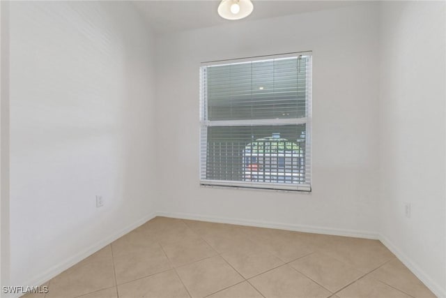 empty room featuring light tile patterned flooring and baseboards