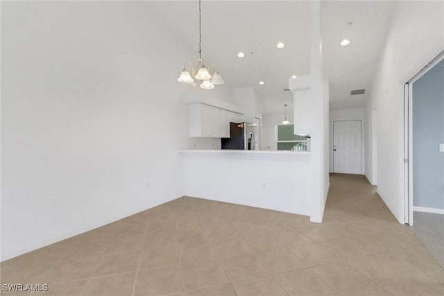 kitchen featuring hanging light fixtures, light countertops, white cabinets, and stainless steel fridge