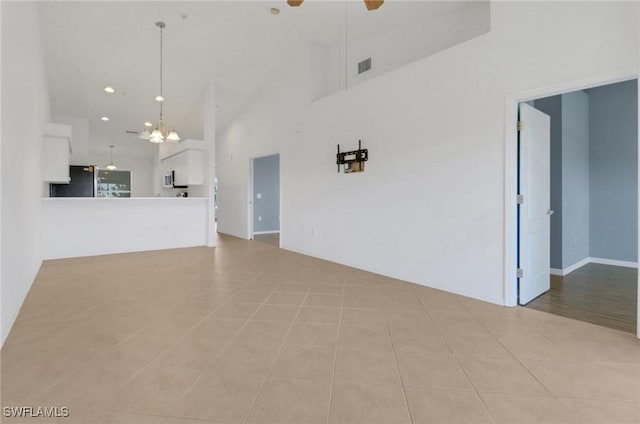 unfurnished living room featuring visible vents, ceiling fan with notable chandelier, recessed lighting, light tile patterned flooring, and a towering ceiling