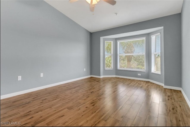 spare room featuring vaulted ceiling, wood finished floors, baseboards, and ceiling fan