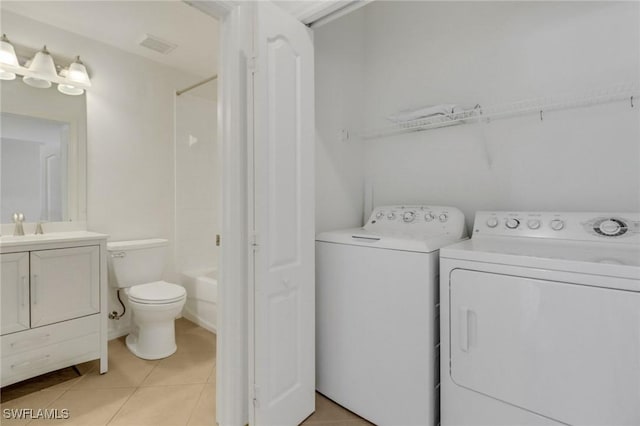 clothes washing area with visible vents, washer and dryer, a sink, light tile patterned floors, and laundry area