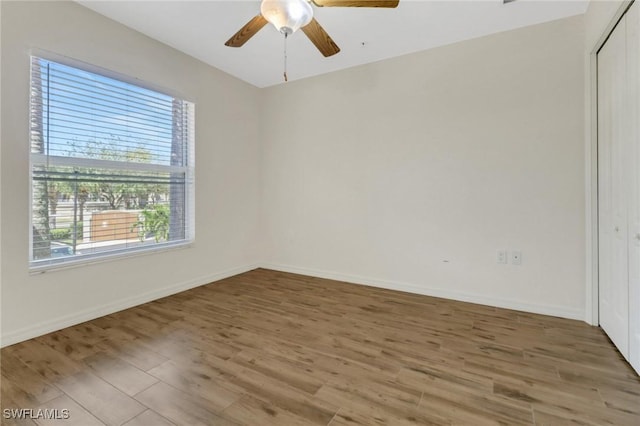 spare room featuring wood finished floors, baseboards, and ceiling fan