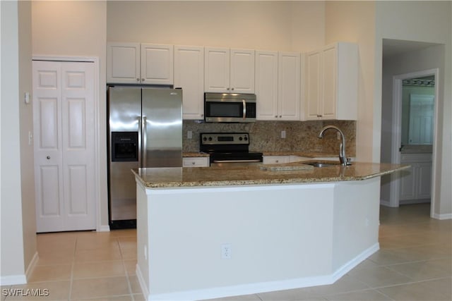 kitchen with light stone counters, light tile patterned floors, a sink, stainless steel appliances, and tasteful backsplash