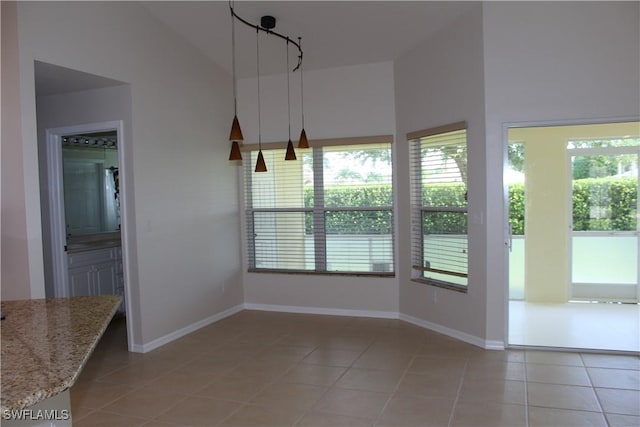 unfurnished dining area featuring light tile patterned floors, baseboards, and high vaulted ceiling