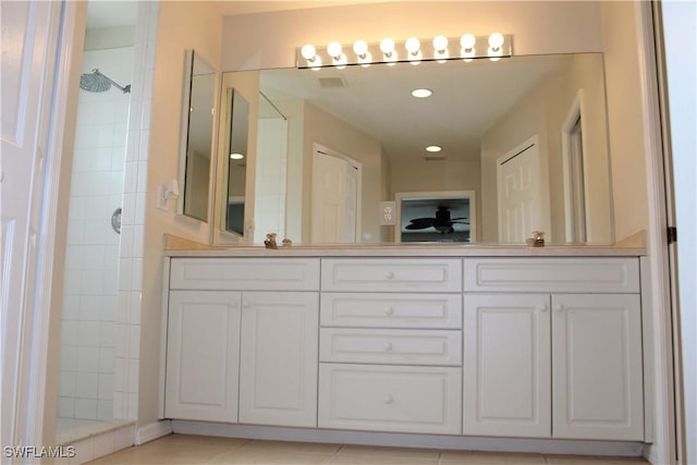 full bathroom featuring double vanity, a tile shower, and a sink