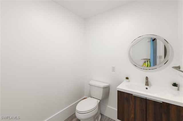 bathroom featuring toilet, vanity, and baseboards