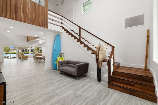 stairs featuring wood finished floors, visible vents, baseboards, and a towering ceiling