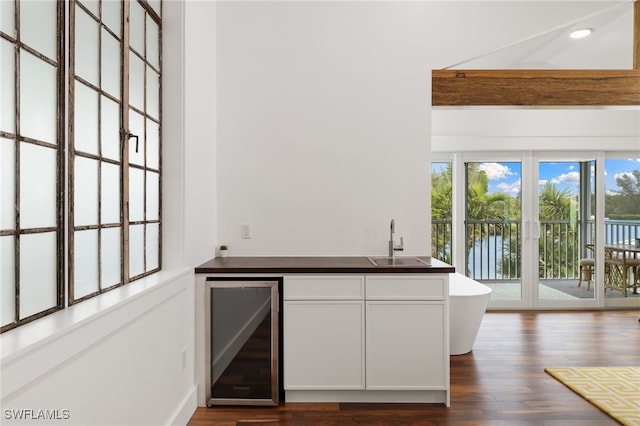 kitchen with dark countertops, beverage cooler, a wealth of natural light, and a sink