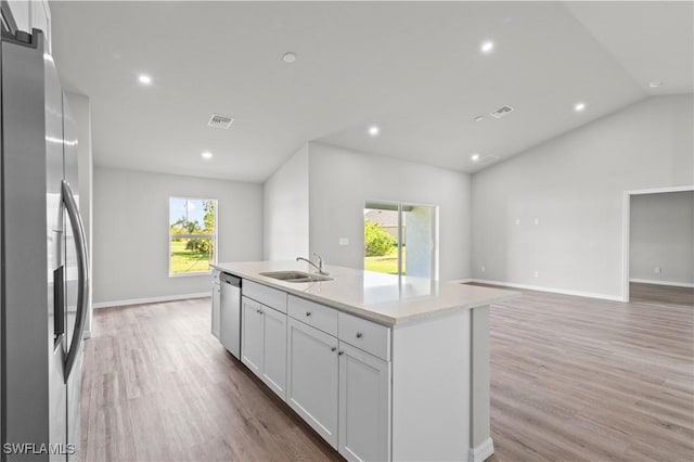 kitchen with lofted ceiling, a sink, white cabinets, appliances with stainless steel finishes, and light wood-type flooring