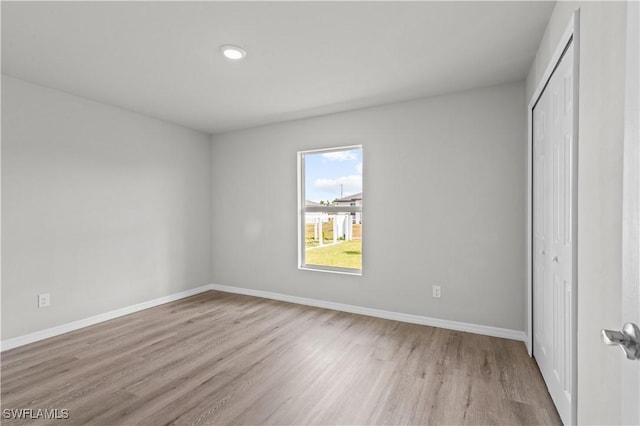 unfurnished bedroom with a closet, baseboards, and wood finished floors