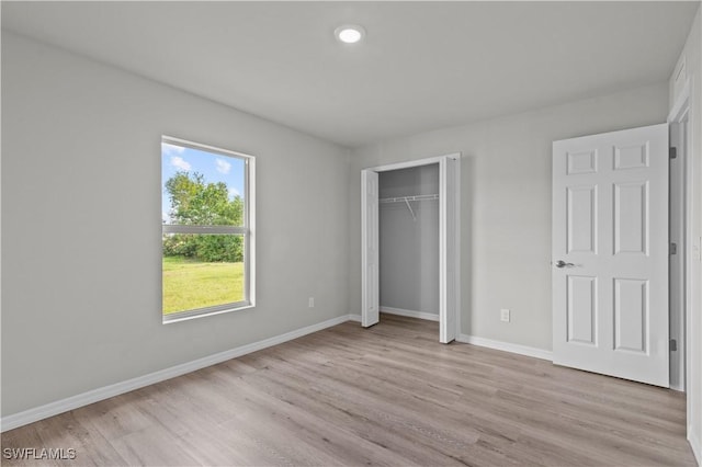 unfurnished bedroom with a closet, baseboards, and light wood-style flooring