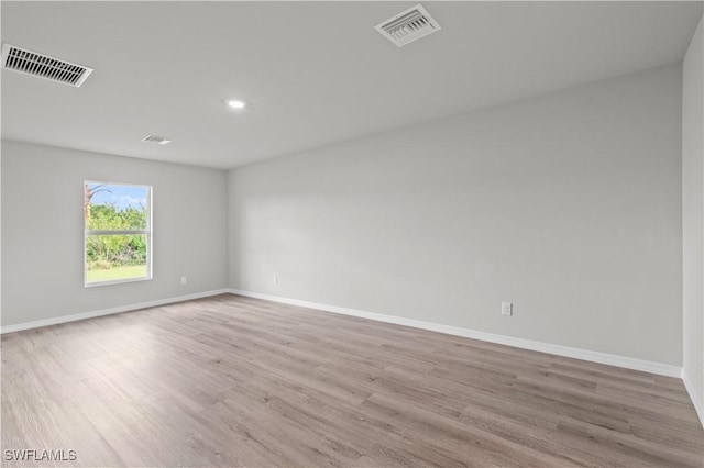 unfurnished room featuring wood finished floors, visible vents, and baseboards