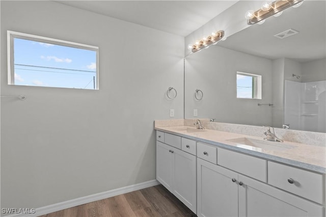 bathroom with visible vents, wood finished floors, baseboards, and a sink