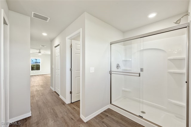 bathroom with a stall shower, visible vents, baseboards, and wood finished floors