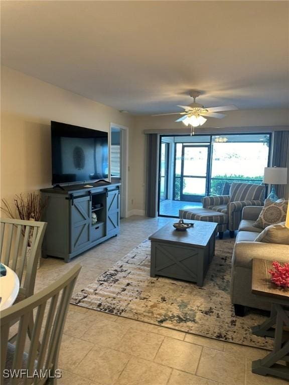 living area with stone finish floor, baseboards, and ceiling fan