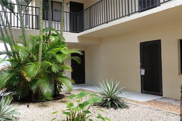 doorway to property with a balcony and stucco siding