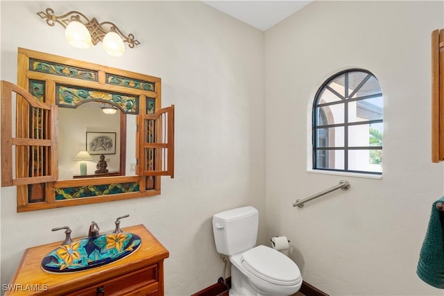 bathroom with toilet, vanity, and baseboards