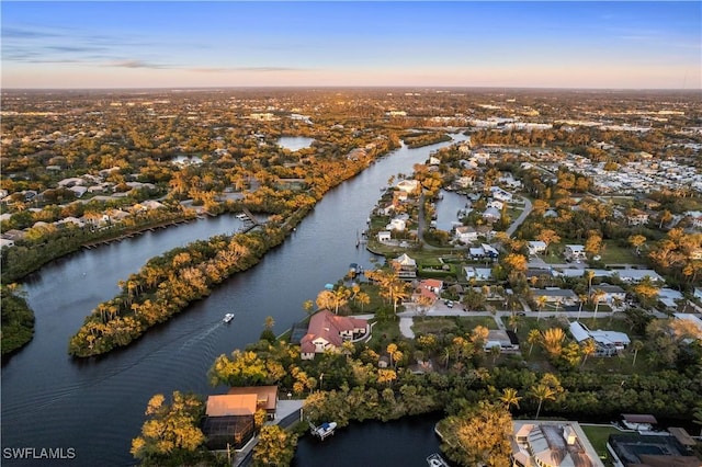 aerial view at dusk featuring a water view