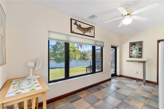 interior space featuring a ceiling fan, baseboards, visible vents, and a water view