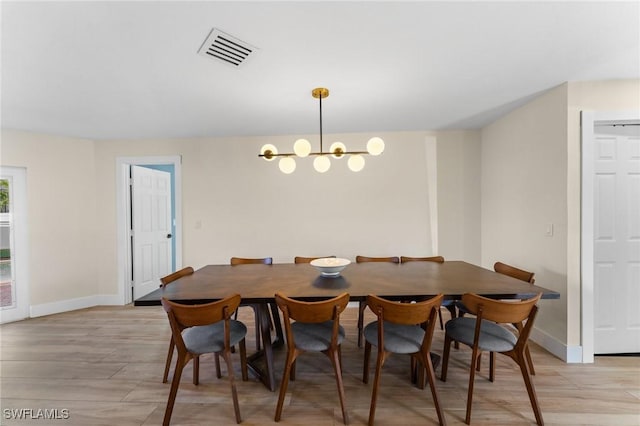 dining area featuring light wood finished floors, visible vents, an inviting chandelier, and baseboards