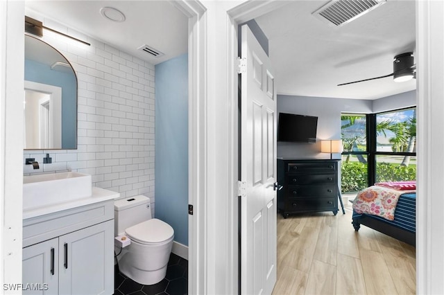 bathroom featuring tile walls, toilet, visible vents, and ceiling fan