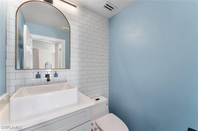 bathroom with vanity, visible vents, tile walls, toilet, and backsplash