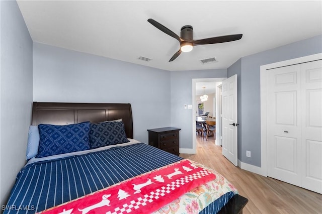 bedroom featuring visible vents, light wood-style flooring, a ceiling fan, and baseboards