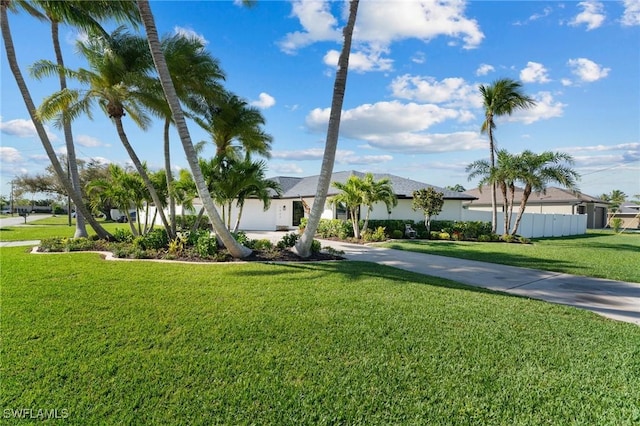 view of front facade featuring concrete driveway, a front lawn, and fence