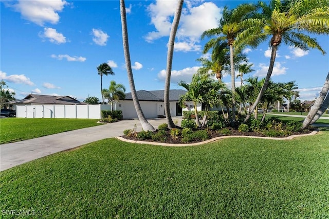 view of yard featuring fence, a garage, and driveway