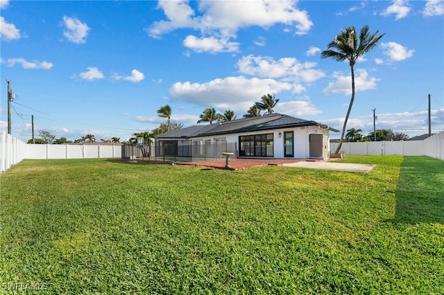 rear view of house featuring a patio, a lawn, and a fenced backyard