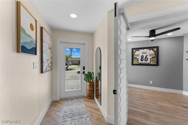 doorway to outside featuring baseboards, recessed lighting, ceiling fan, light wood-style floors, and a barn door