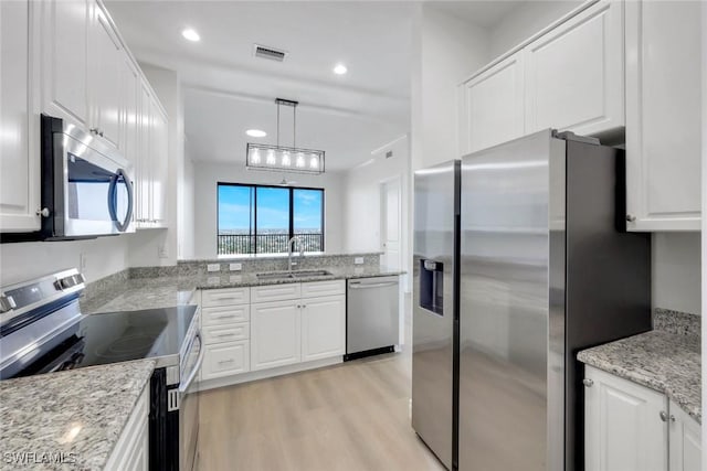 kitchen with visible vents, white cabinetry, stainless steel appliances, and a sink