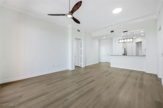 unfurnished living room featuring visible vents, ornamental molding, wood finished floors, baseboards, and ceiling fan