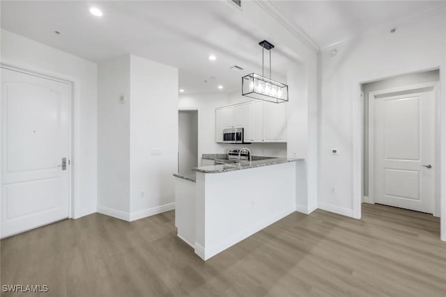 kitchen featuring white cabinets, light stone counters, wood finished floors, and stainless steel appliances