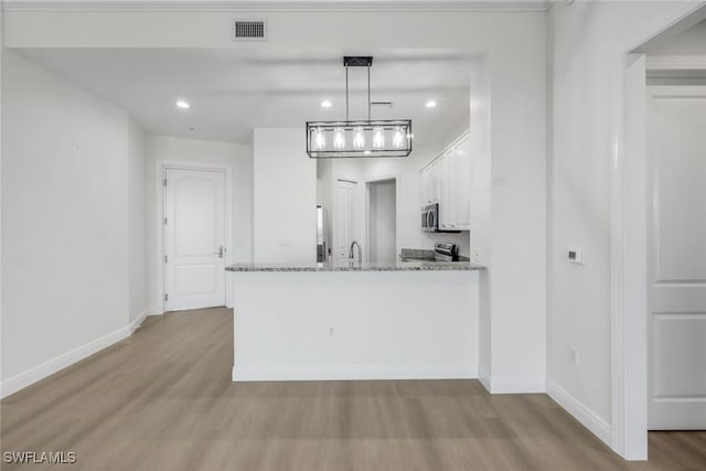 kitchen featuring visible vents, wood finished floors, white cabinetry, stainless steel appliances, and baseboards