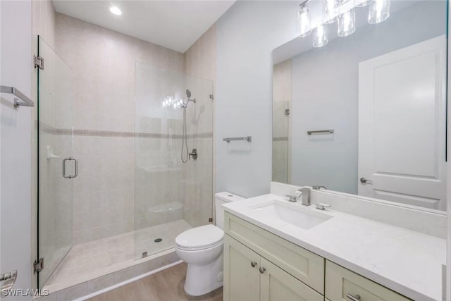 bathroom featuring vanity, a shower stall, toilet, and wood finished floors