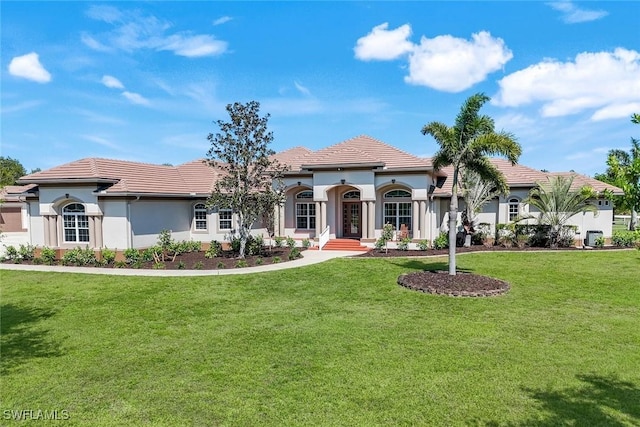 mediterranean / spanish house with a front lawn, a tiled roof, and stucco siding