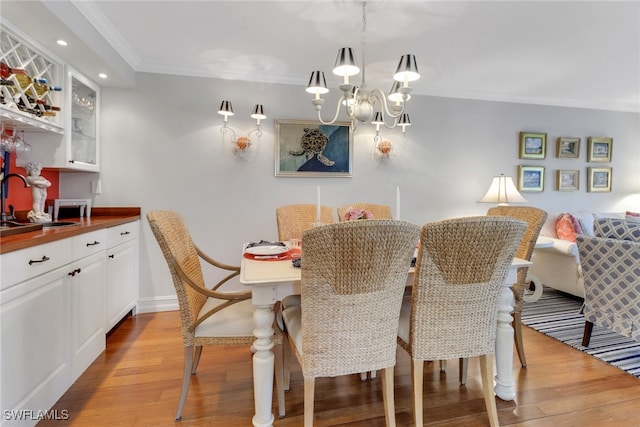 dining space with crown molding, baseboards, recessed lighting, light wood-style flooring, and an inviting chandelier