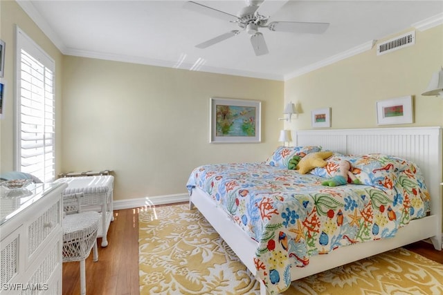 bedroom featuring crown molding, wood finished floors, visible vents, and baseboards