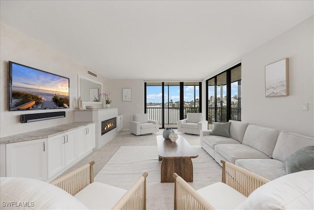 living area featuring a glass covered fireplace, expansive windows, and light carpet