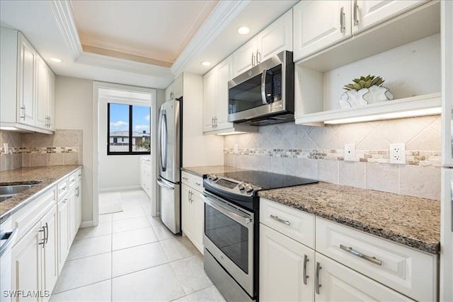 kitchen with a tray ceiling, stainless steel appliances, crown molding, and white cabinetry